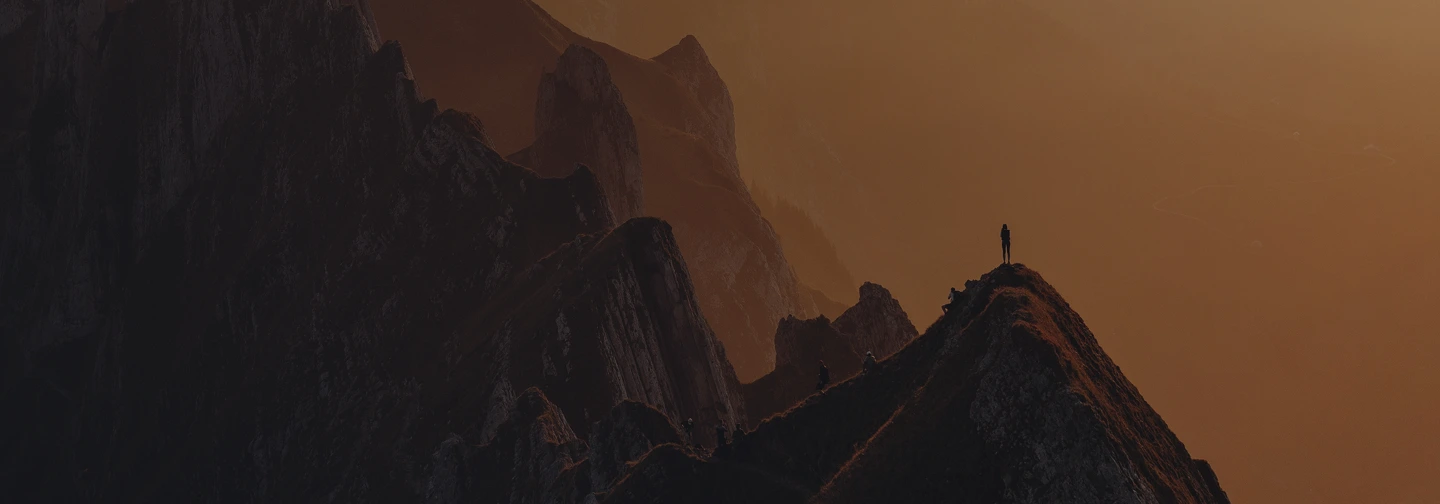 Homme debout sur le sommet d'une montagne au coucher de soleil